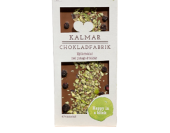 En bild som visar Happy in a blink - Handgjord och ekologisk chokladkaka i mjölkchoklad med blåbär och pistagenötter tillverkad i Sverige av Kalmar Chokladfabrik.